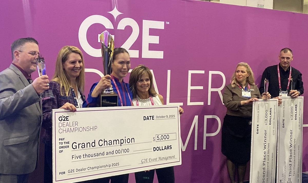 Dealer championship winner Elleonor Hoffman stands with check for $5,000 while other two finalist Madalina Restia and Mark Vekovic look onward holding their checks off to the right.