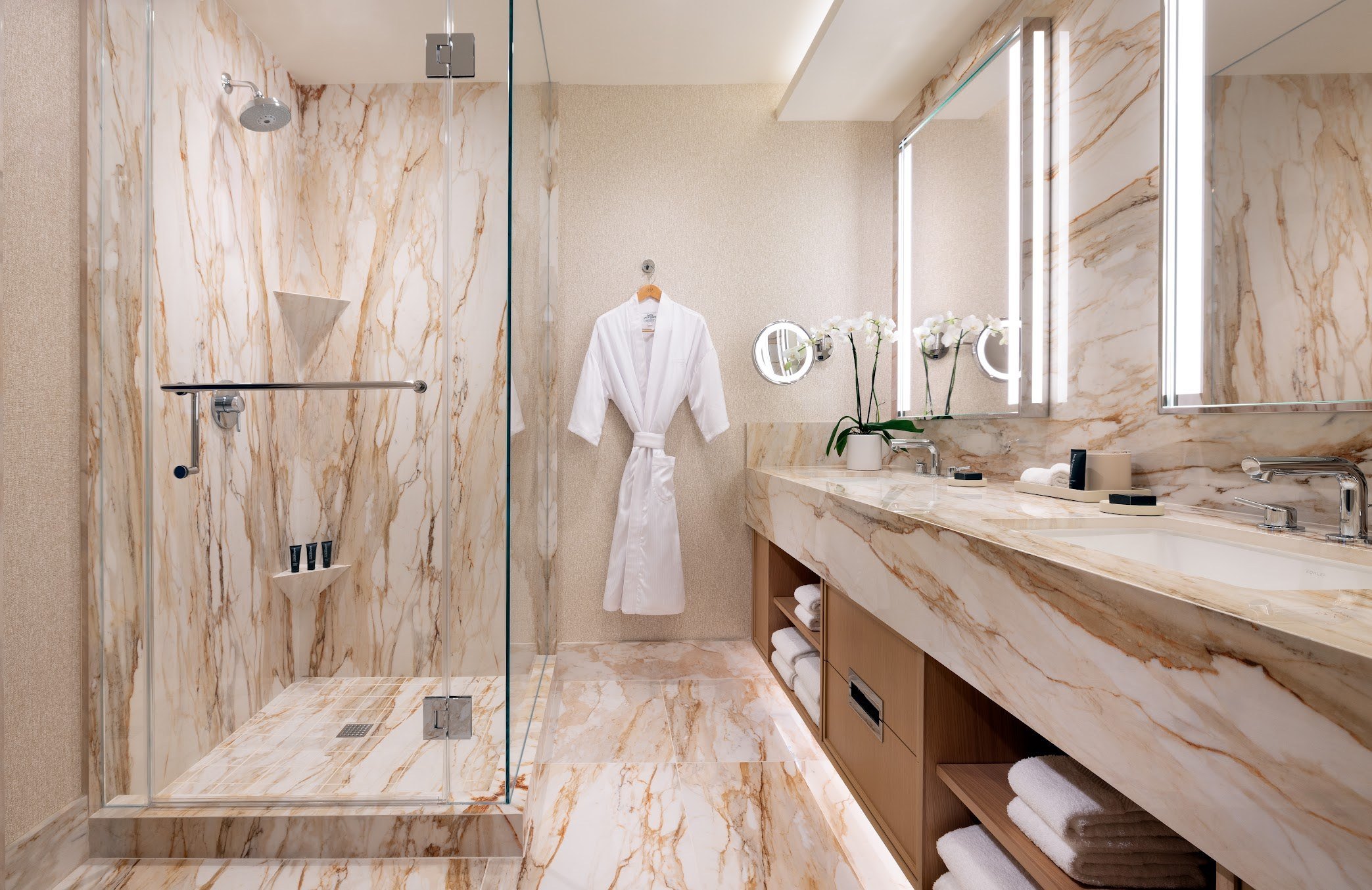 Renovated bathroom at Green Valley Ranch with a marble walk-in shower, double vanity with LED lights, and luxury counter finishes.